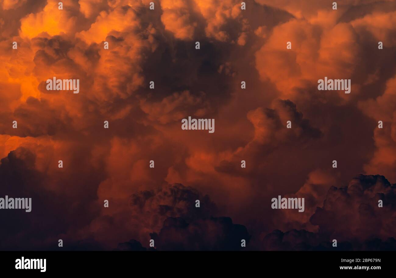 Red, orange fluffy clouds on sunset sky background. Art picture of orange clouds texture. Beautiful pattern of clouds. Dark and horror scene of sky. Stock Photo