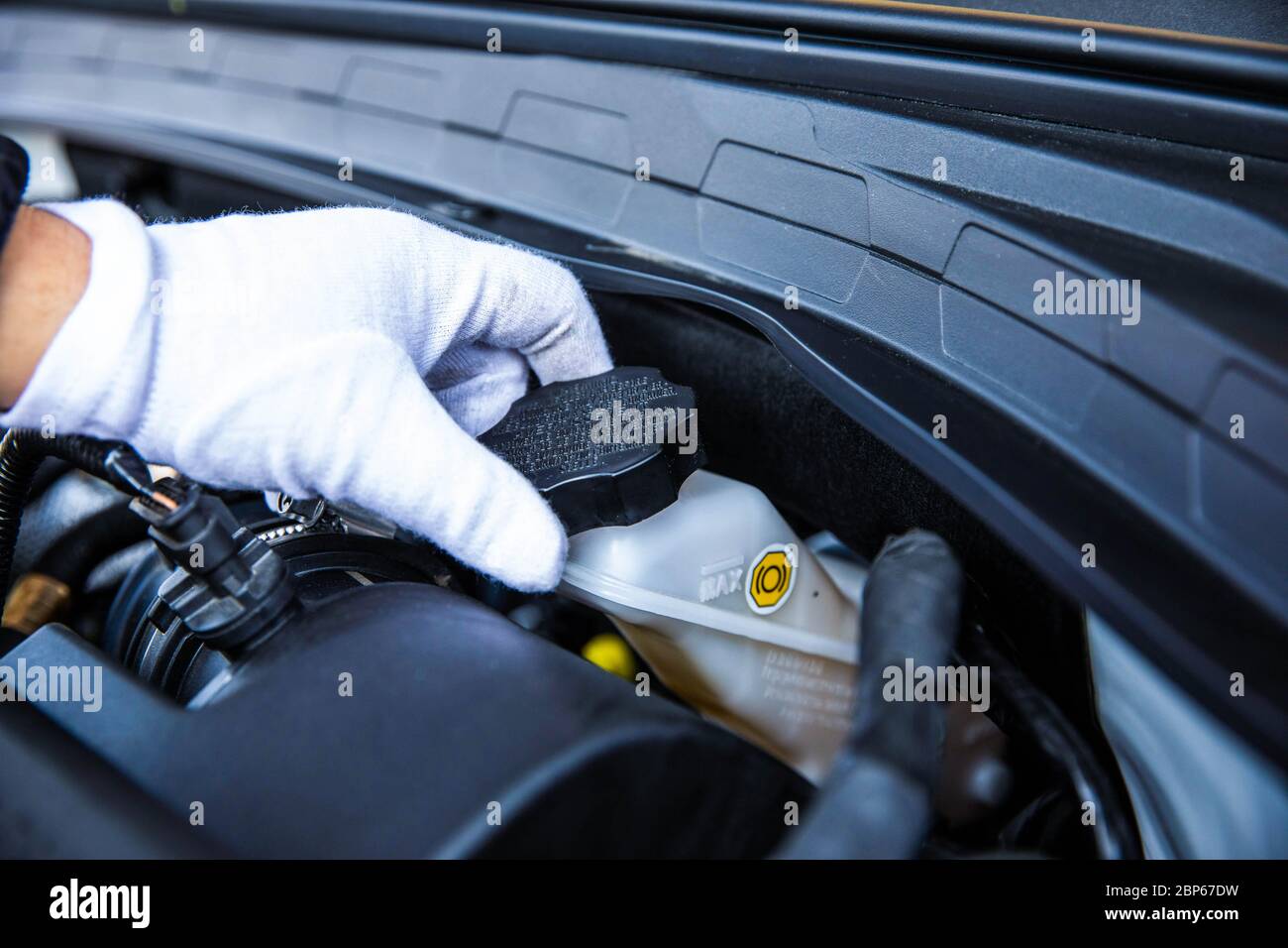 Hand opening a car engine coolant reservoir. Stock Photo