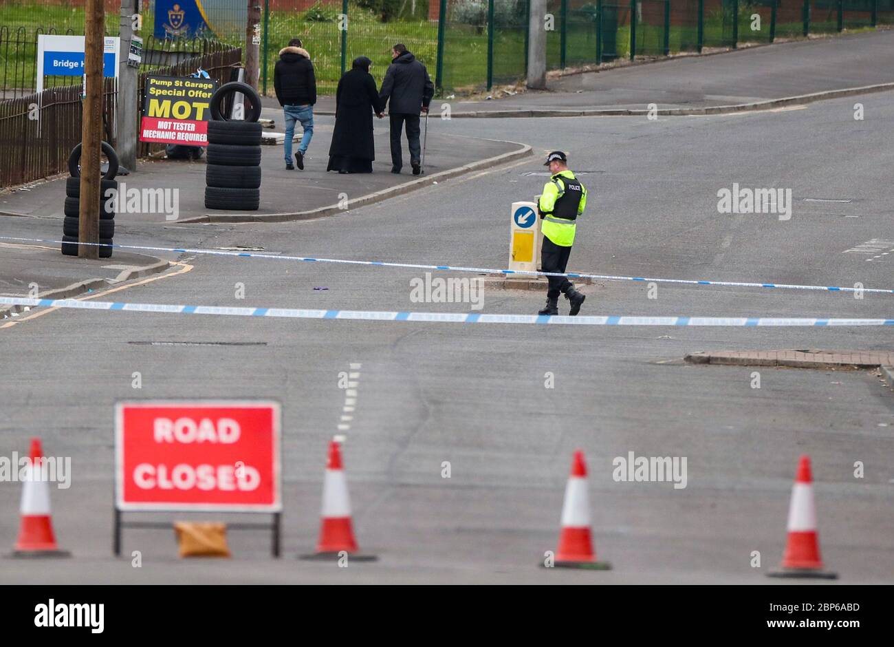 A family leave the scene where police officers have cordoned off part of King Street, Blackburn, following the death of a woman from a suspected gunshot wound on Sunday. Stock Photo