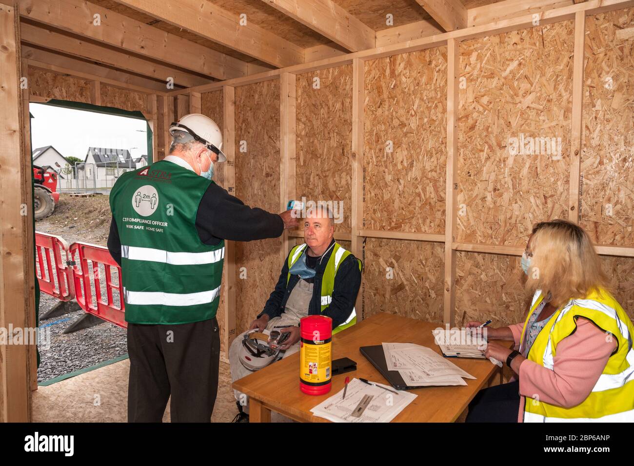 Carrigaline, Cork, Ireland. 18th May, 2020.On the first day of phase one with the easing of Covid-19 restrictions Safety Officer Michael O'Sullivan checks the temperture of one of the workers assisted by Caroline O'Keffee at the Astra construction site in Janeville, Carrigaline, Co. Cork, Ireland. - Credit; David Creedon / Alamy Live News Stock Photo