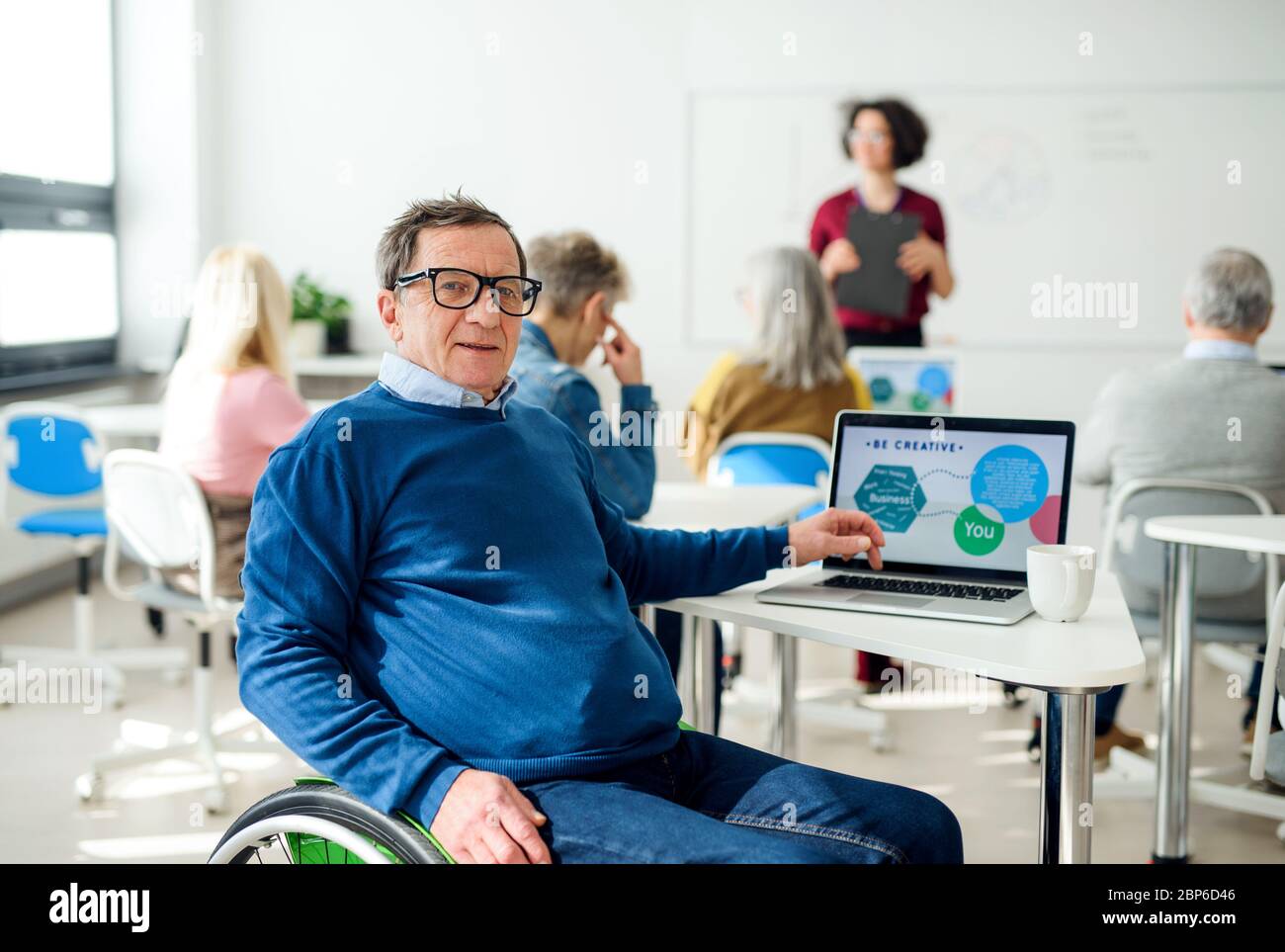 Senior man in wheelchair attending computer and technology education class. Stock Photo