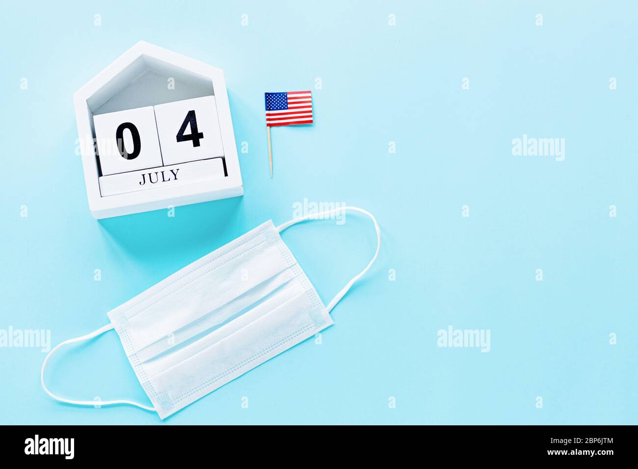 July 4th. USA flag and medical mask on blue background. Independence Day Of America 2020 during coronavirus covid-19 pandemic quarantine. Flat lay Stock Photo