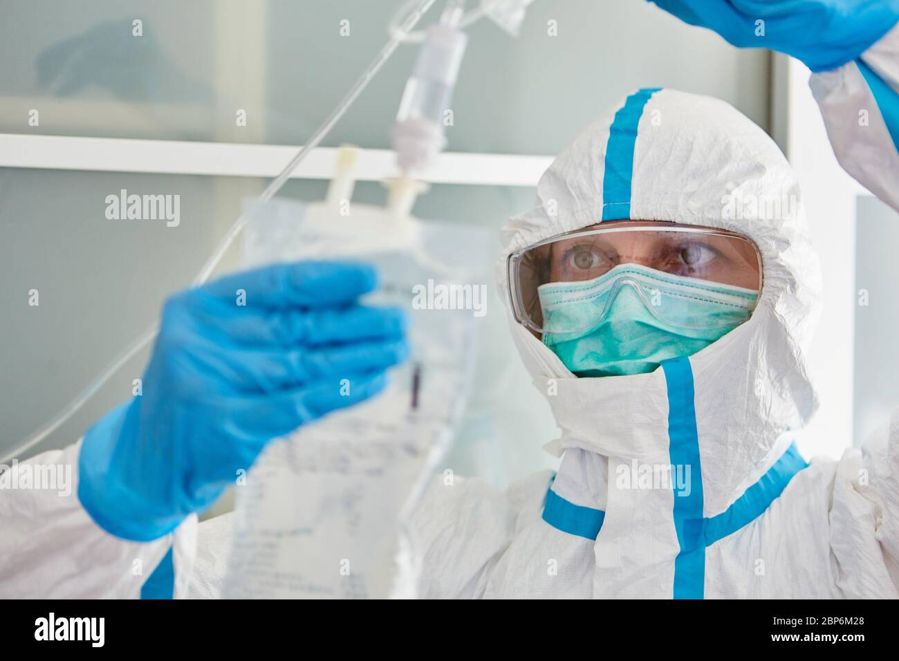 Doctor in protective clothing in hospital intensive care unit prepares infusion for Covid-19 patient during coronavirus pandemic Stock Photo