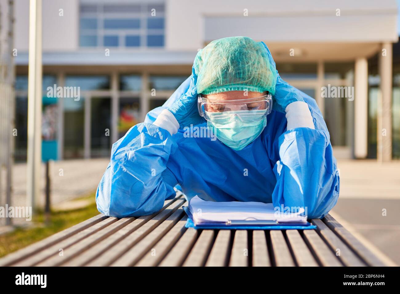 Nursing staff in front of clinic studies thoughtful or exhausted list for contact tracking during the coronavirus Stock Photo