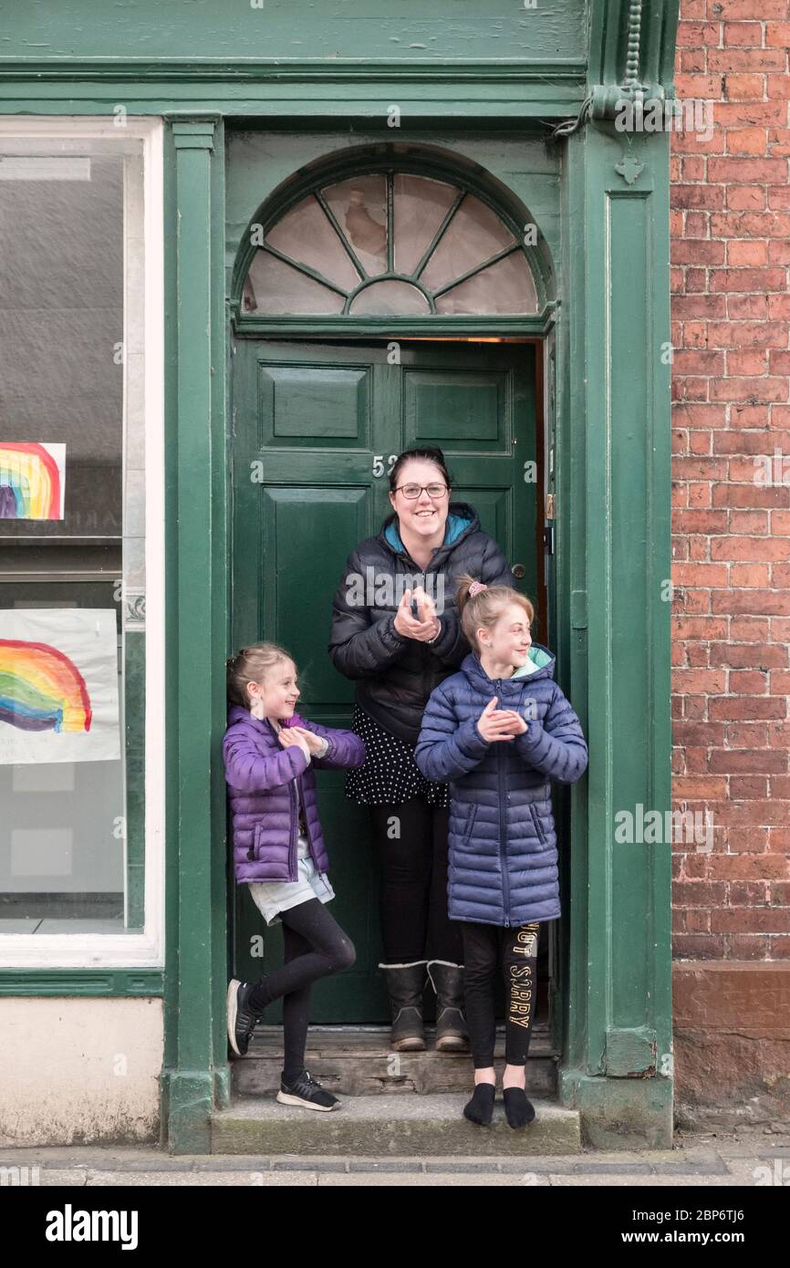 A family at their front door during the weekly Clap for our Carers event, Presteigne, Powys, Wales, UK Stock Photo