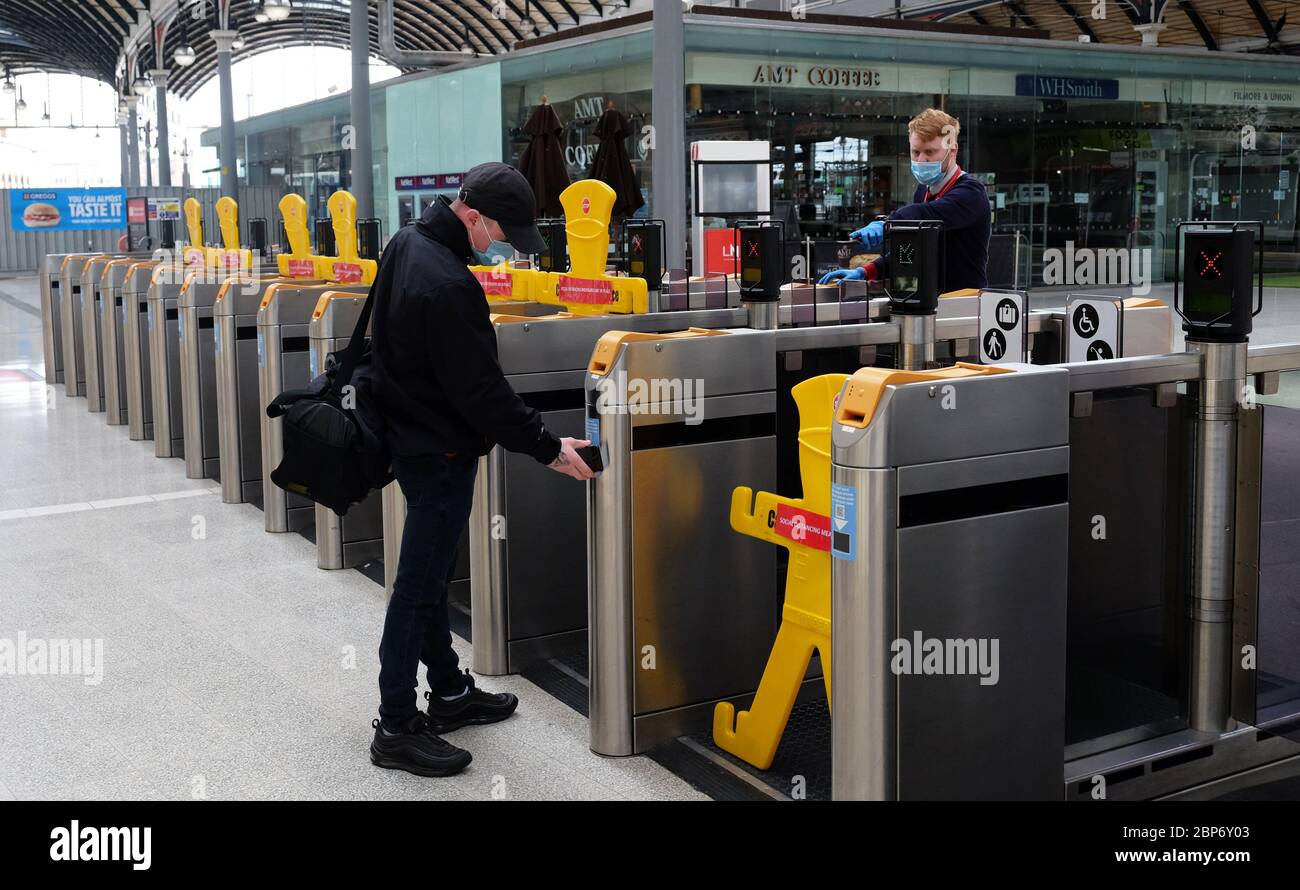 A passenger scans his ticket at barriers that have been blocked for social distancing measures at Newcastle train station, as train services increase as part of the easing of coronavirus lockdown restrictions. Stock Photo