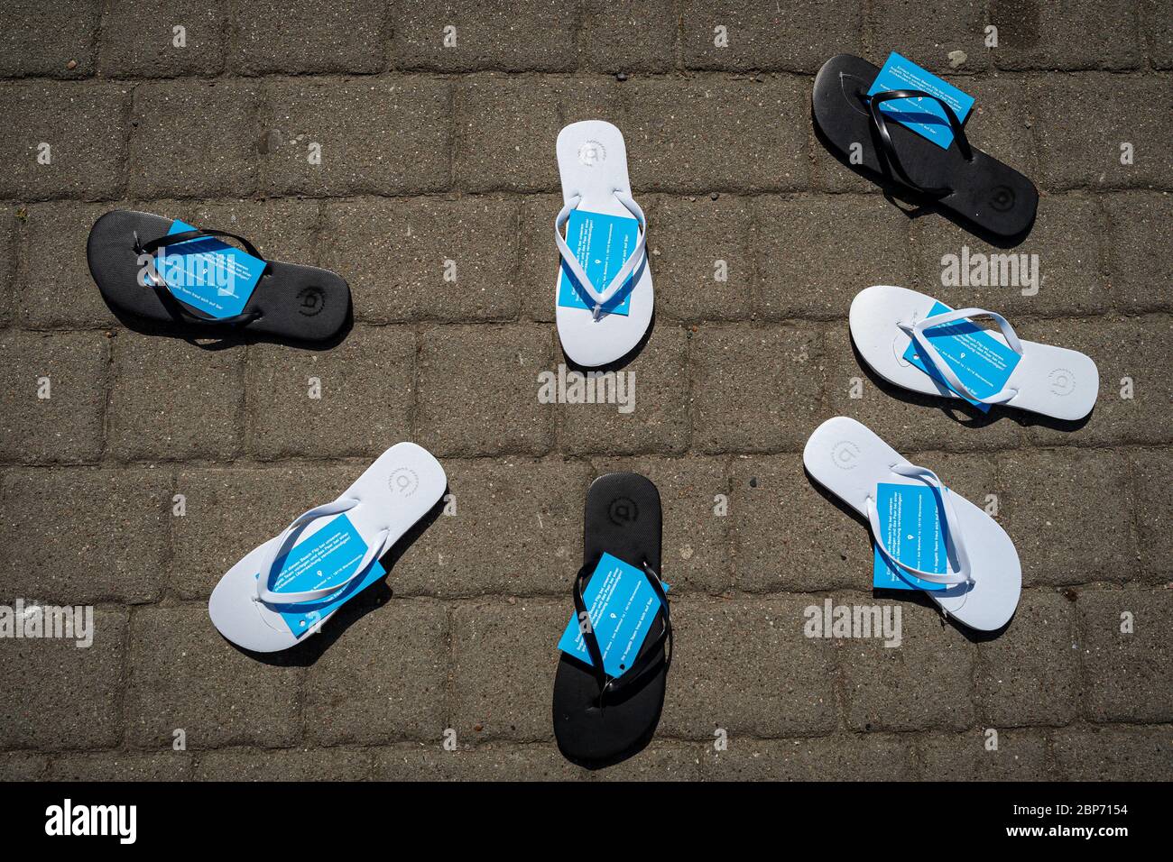 WARNEMUENDE (ROSTOCK), GERMANY - JULY 25, 2019: Flip flops lie on the pavement in a semicircle. Unusual advertising campaign shoe store. Stock Photo