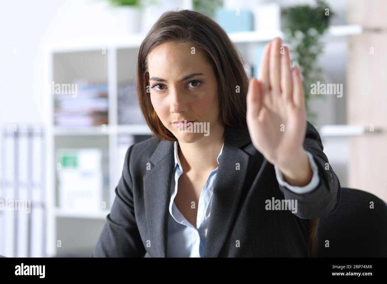 Serious executive woman looking at camera gesturing stop sitting at the office Stock Photo
