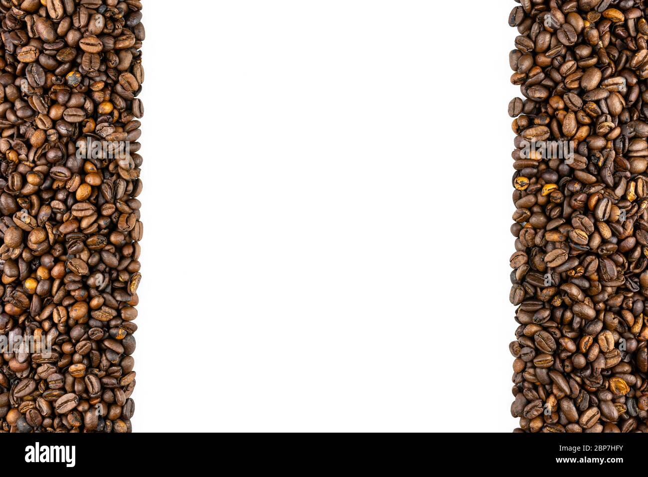 Background made of fresh roasted coffee beans lying flat on a white background with copy space, filled on the sides from top to bottom. Stock Photo