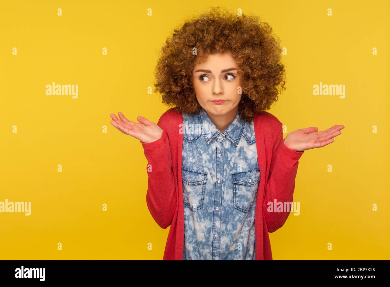 Don't know, maybe. Portrait of clueless uncertain confused woman with fluffy curly hair raising hands in hesitations, doubting and thinking careless, Stock Photo