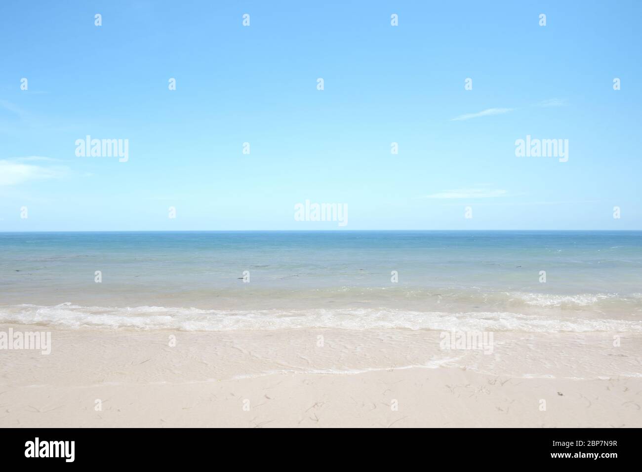 Sandy beach with the blue ocean and blue sky background Stock Photo - Alamy