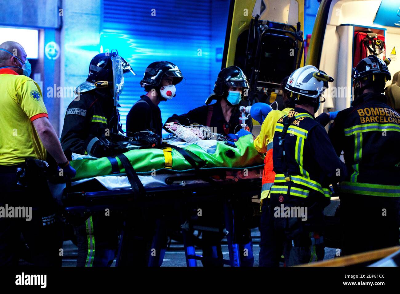 An elderly person suspected of having Corvid-19 is helped into an ambulance by firemen and healthcare workers. Stock Photo