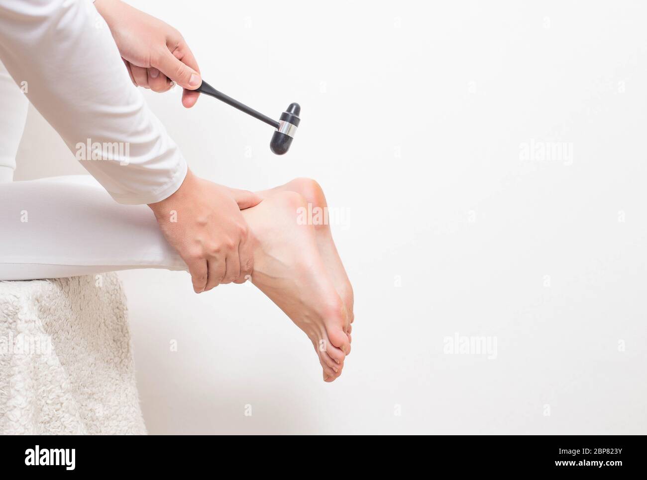 A neurologist doctor checks the Achilles reflex with a neurological hammer. Checking the tibial nerve and the presence of an intervertebral hernia of Stock Photo