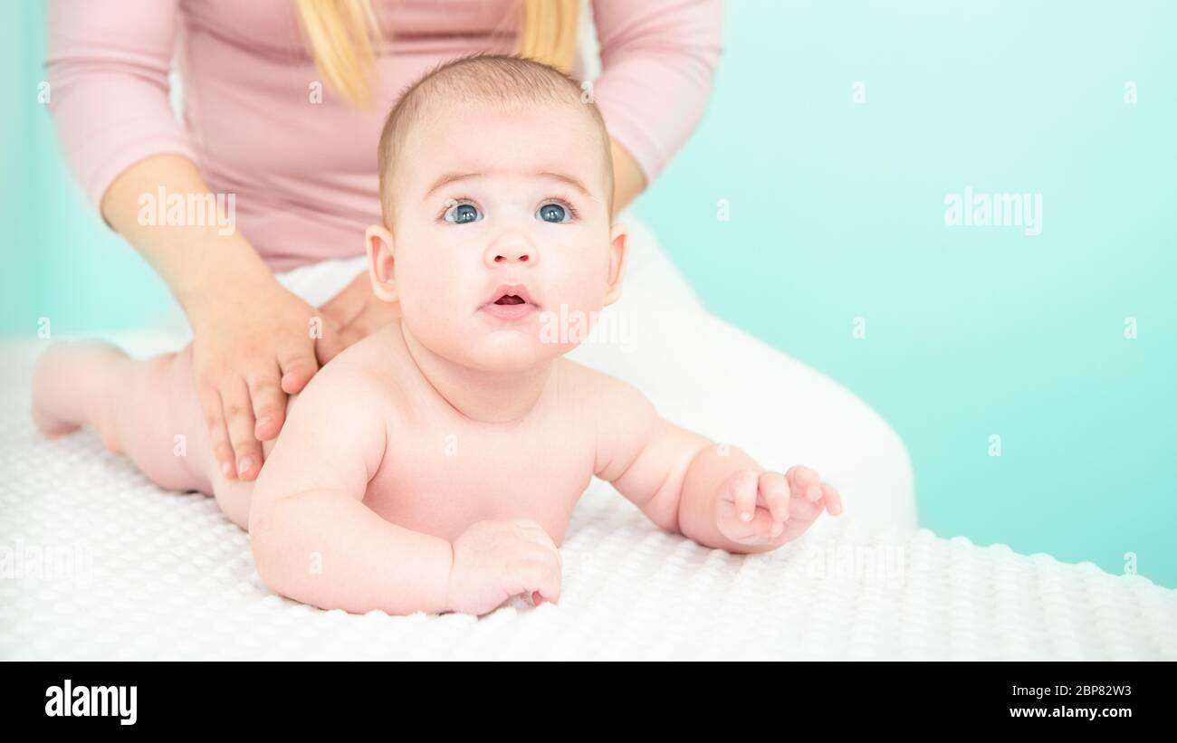Baby massage background. Young therapist giving a baby boy a back