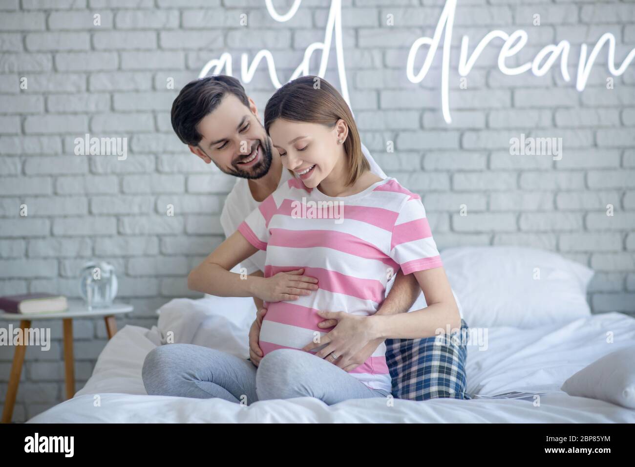 Dark-haired man hugging his cute pregnant wife Stock Photo - Alamy