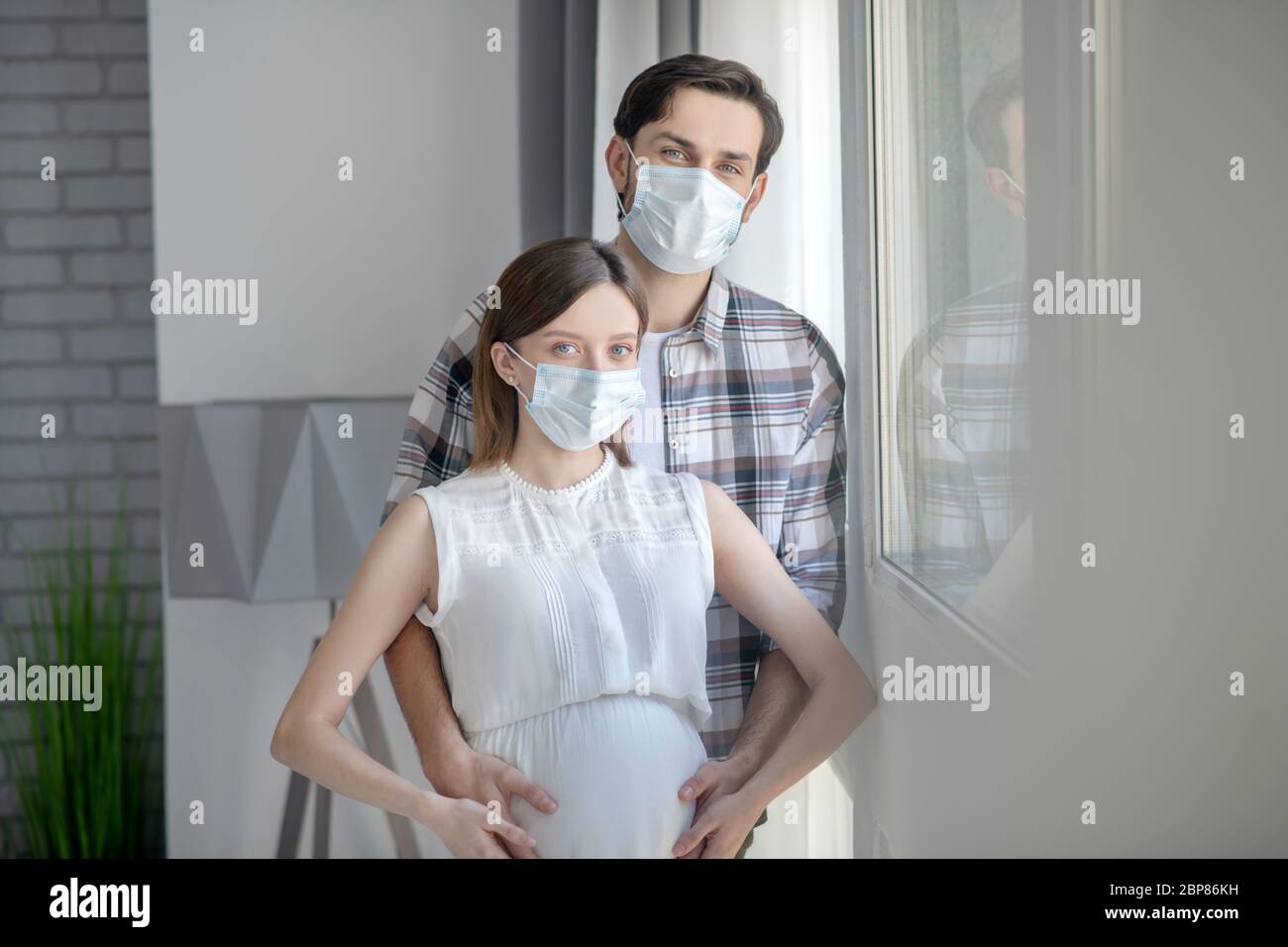 Tall man in a mask hugging his pregnant wife Stock Photo - Alamy
