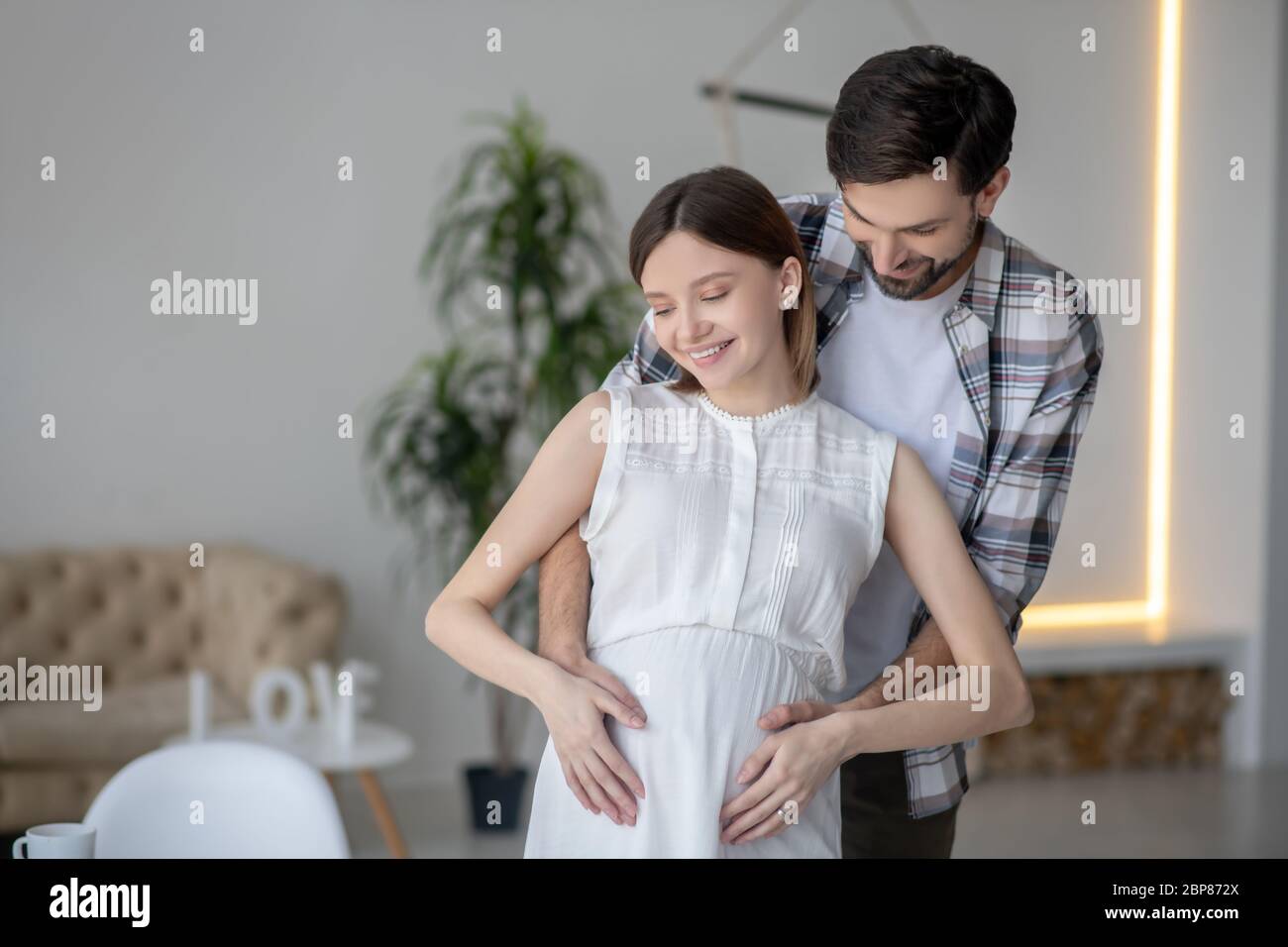 Dark-haired bearded man hugging his pregnant wife Stock Photo - Alamy