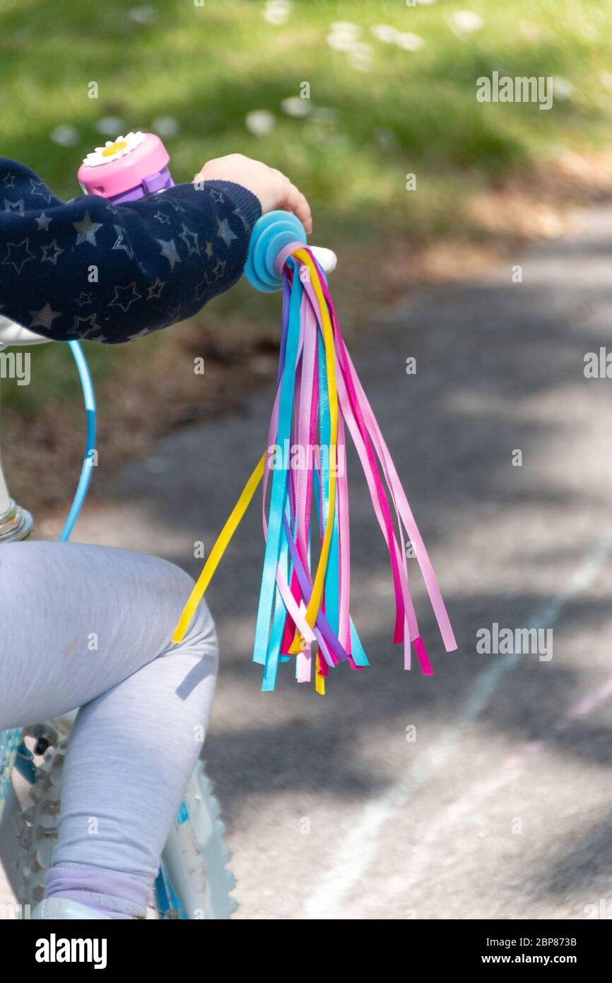 a close up view of bright coloured tassels attached to a little girls bike Stock Photo