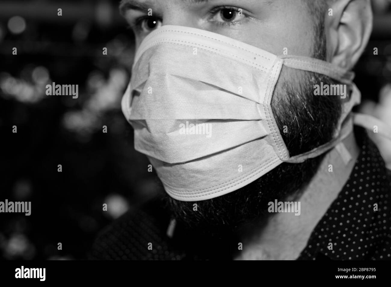 Black and white close up of a bearded man wearing a surgical mask ...