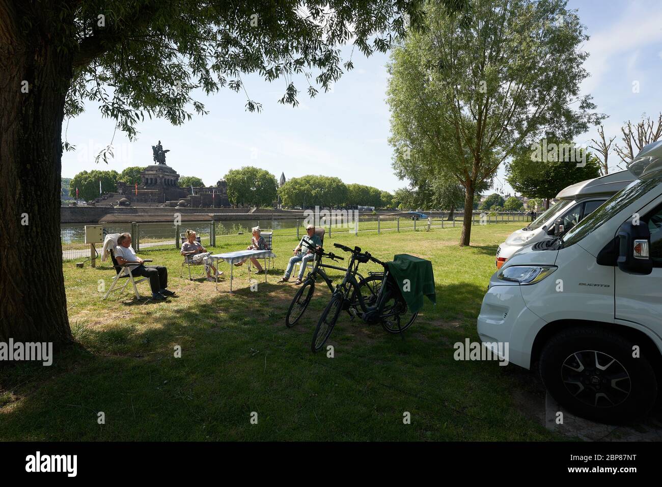 Koblenz, Germany. 18th May, 2020. Tourists from Osnabrück sit in the sun in  front of their mobile homes on the campsite opposite the Deutsches Eck.  Camping sites and hotels are open again