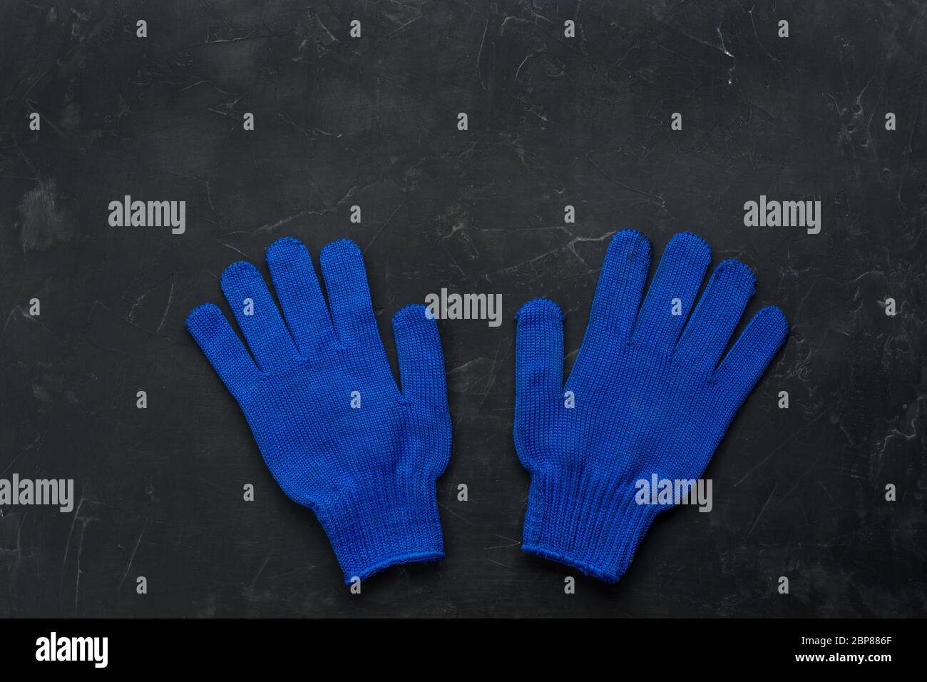 Blue working gloves over dark background, construction tools. Minimal black Stock Photo