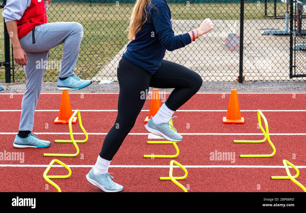 Two high school track sprinters performing sprint and form drill