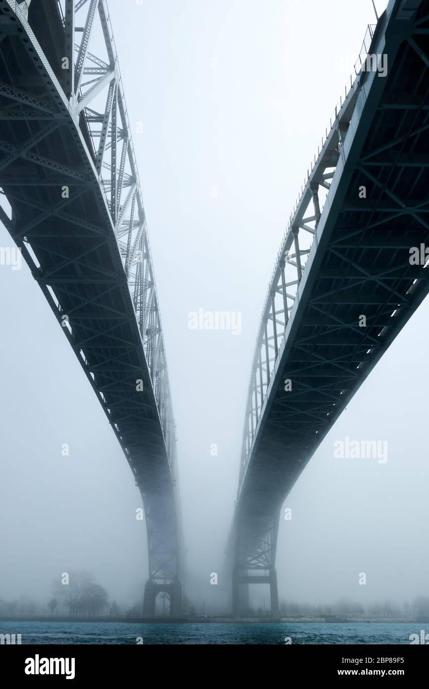 Fog surrounding twin span of bridges over river. Path leading to unknown future of coming out of the mist. Stock Photo
