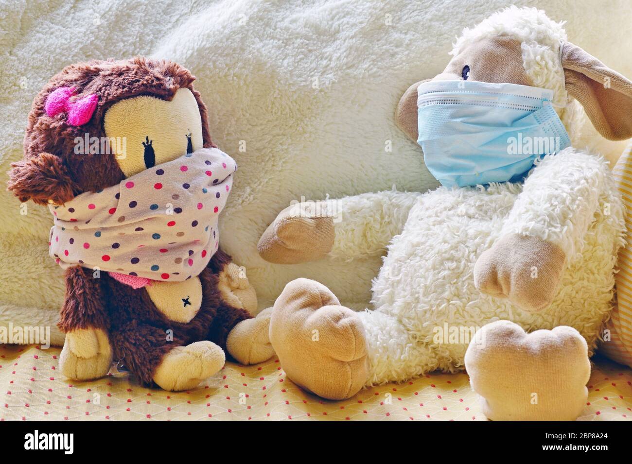 Two childrens plush stuffed animal toys earing a face mask during the