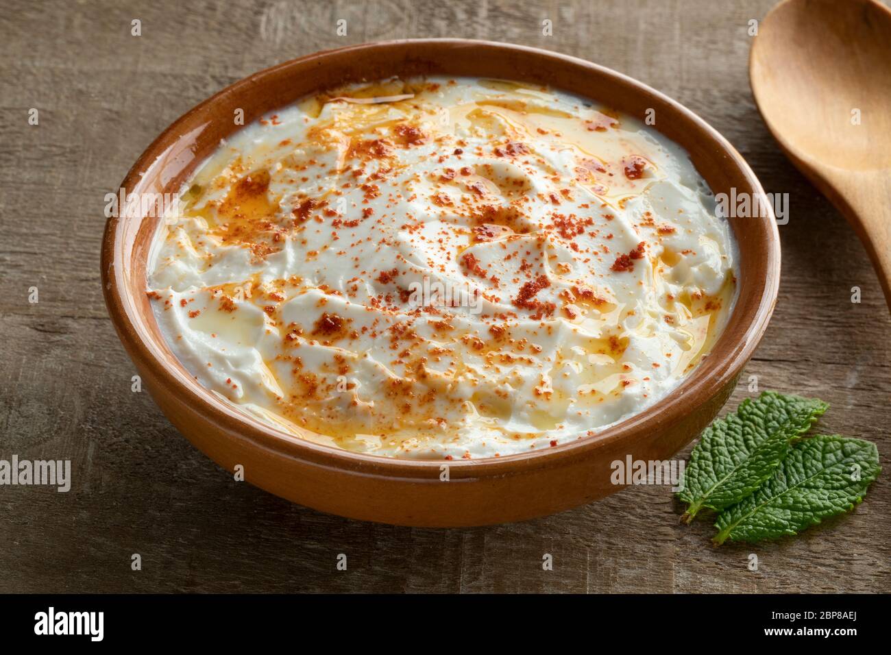 Bowl with Lebanese labneh with olive oil and sprinkled with herbs Stock Photo