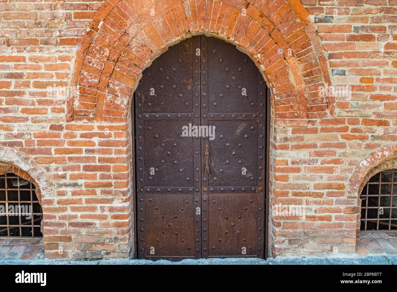 Old metal door of an old bricked house in Piedmont Asti, Italy Stock Photo