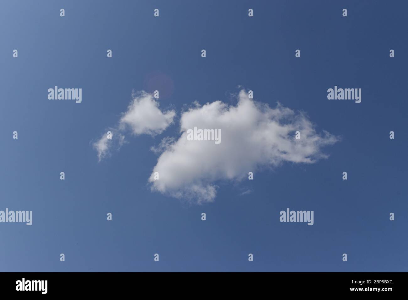 Single white cloud on blue sky background. Stock Photo