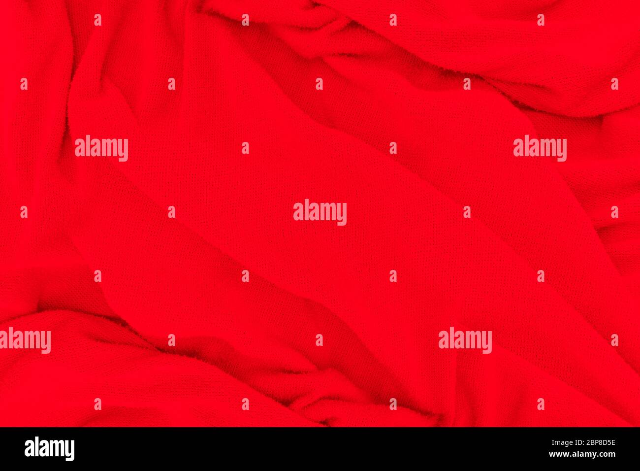 Red fabric texture background. Abstract cloth backdrop with soft waves. Stock Photo