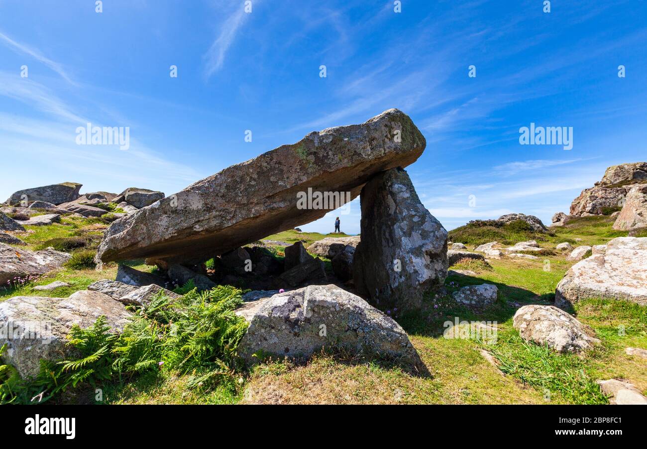 A walker on the Pembrokeshire Coast Path through the Coetan Arthur Neolithic burial chamber at St David's Head, Wales Stock Photo