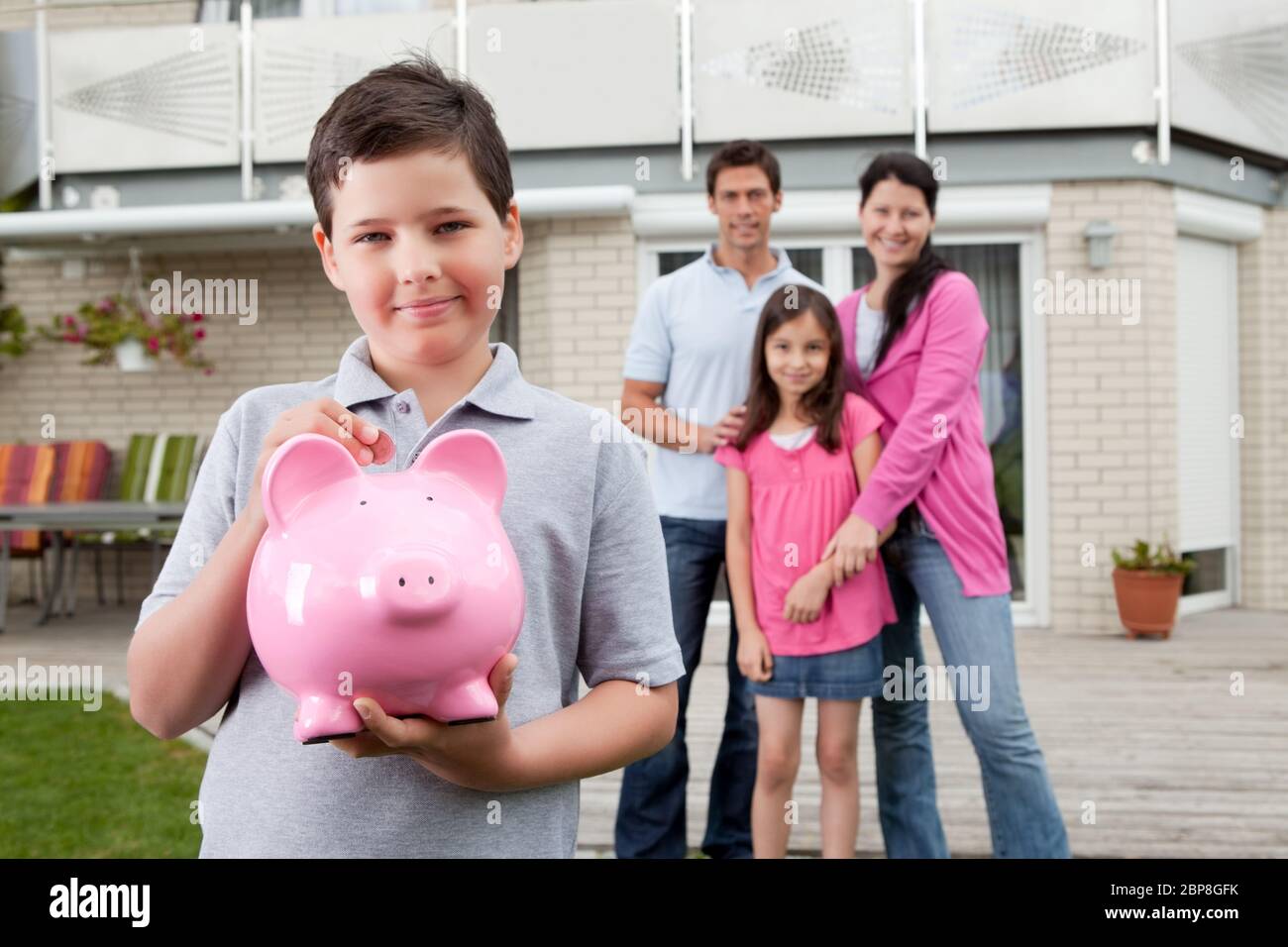 Adorable little boy inserting coin in a piggy bank with her family in ...