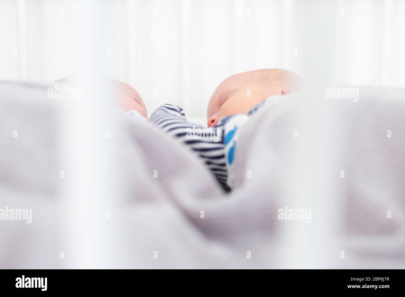 Three week old newborn male and female twins sleeping in a cot born