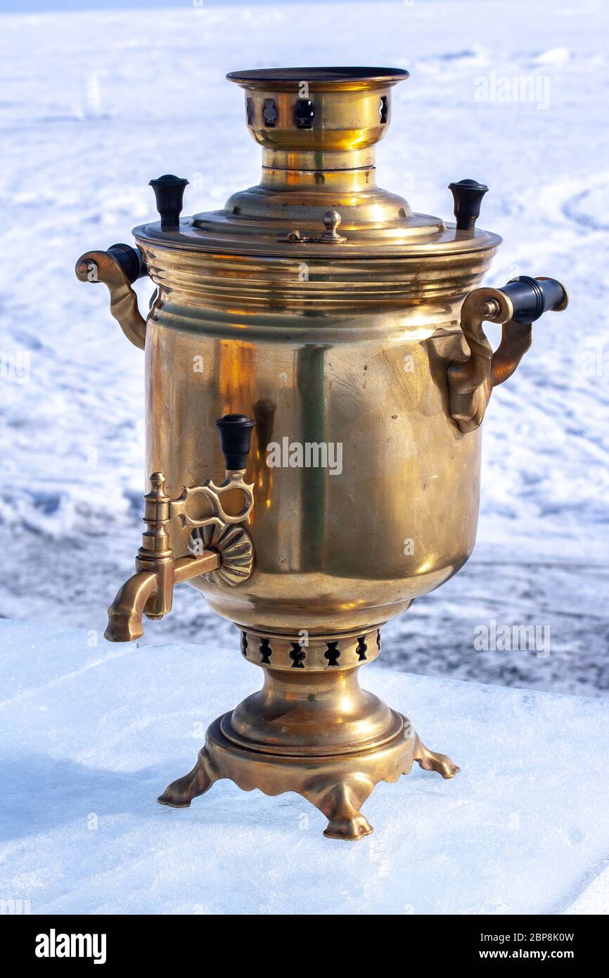 A brilliant samovar stands on an ice plate against a snow background. Large  Russian wood-fired kettle. Made of copper and brass. Blurred background. V  Stock Photo - Alamy