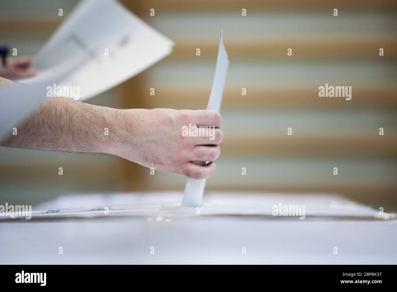 Hand of a person casting a ballot at a polling station during voting ...