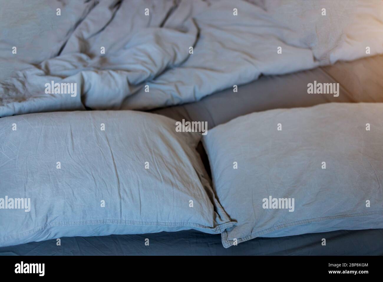 Closeup of gray pillows and blankets with a sheet on the bed Stock Photo
