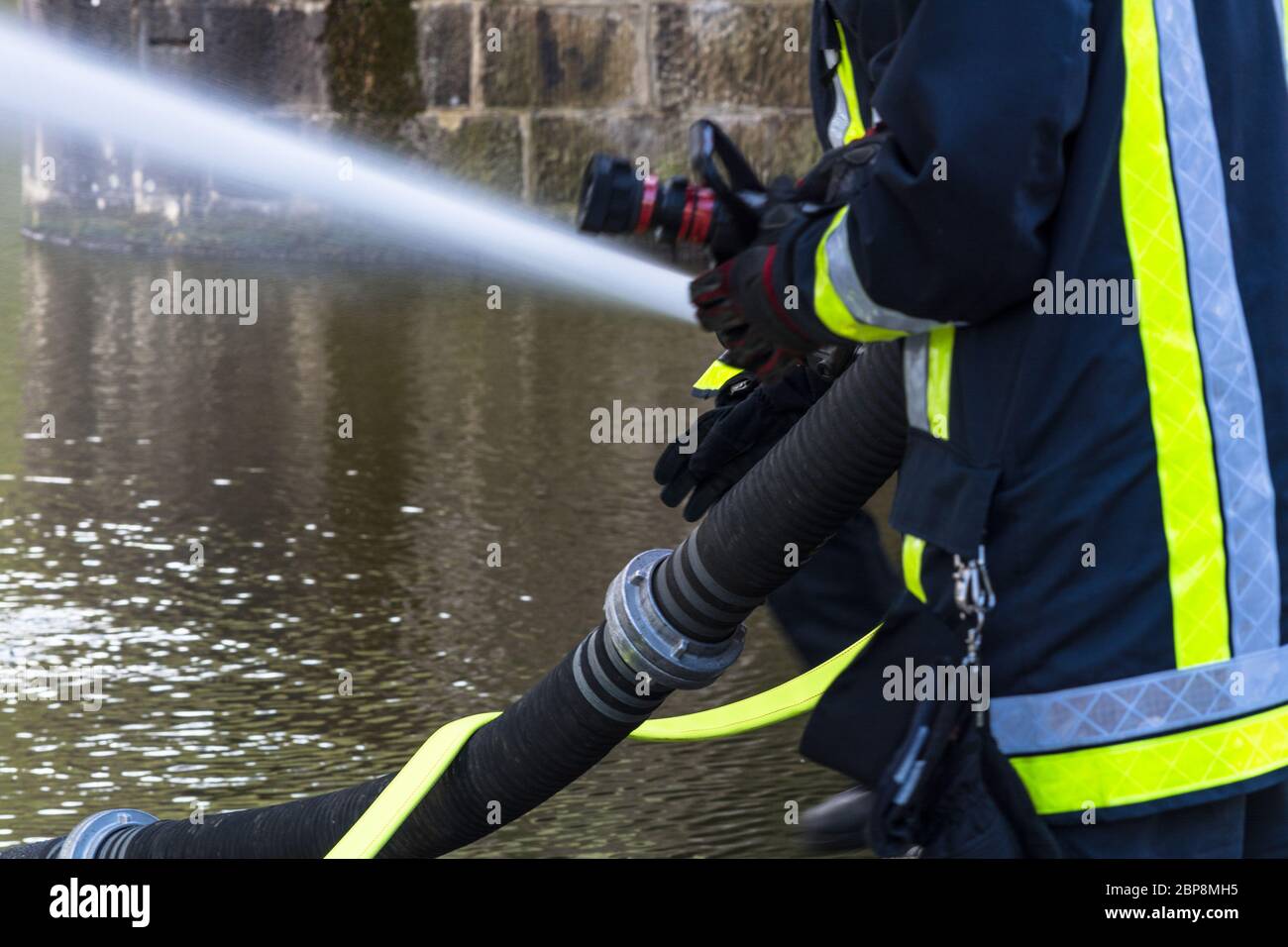 Feuerwehr sprüht Löschwasser aus Feuerwehrschläuchen während einer Übung. Stock Photo