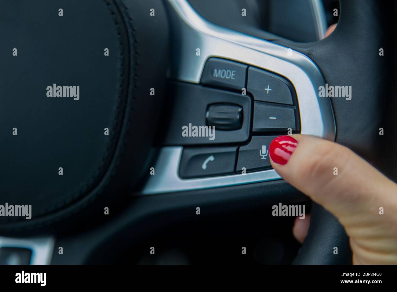 finger of a female hand push the microphone button on the steering