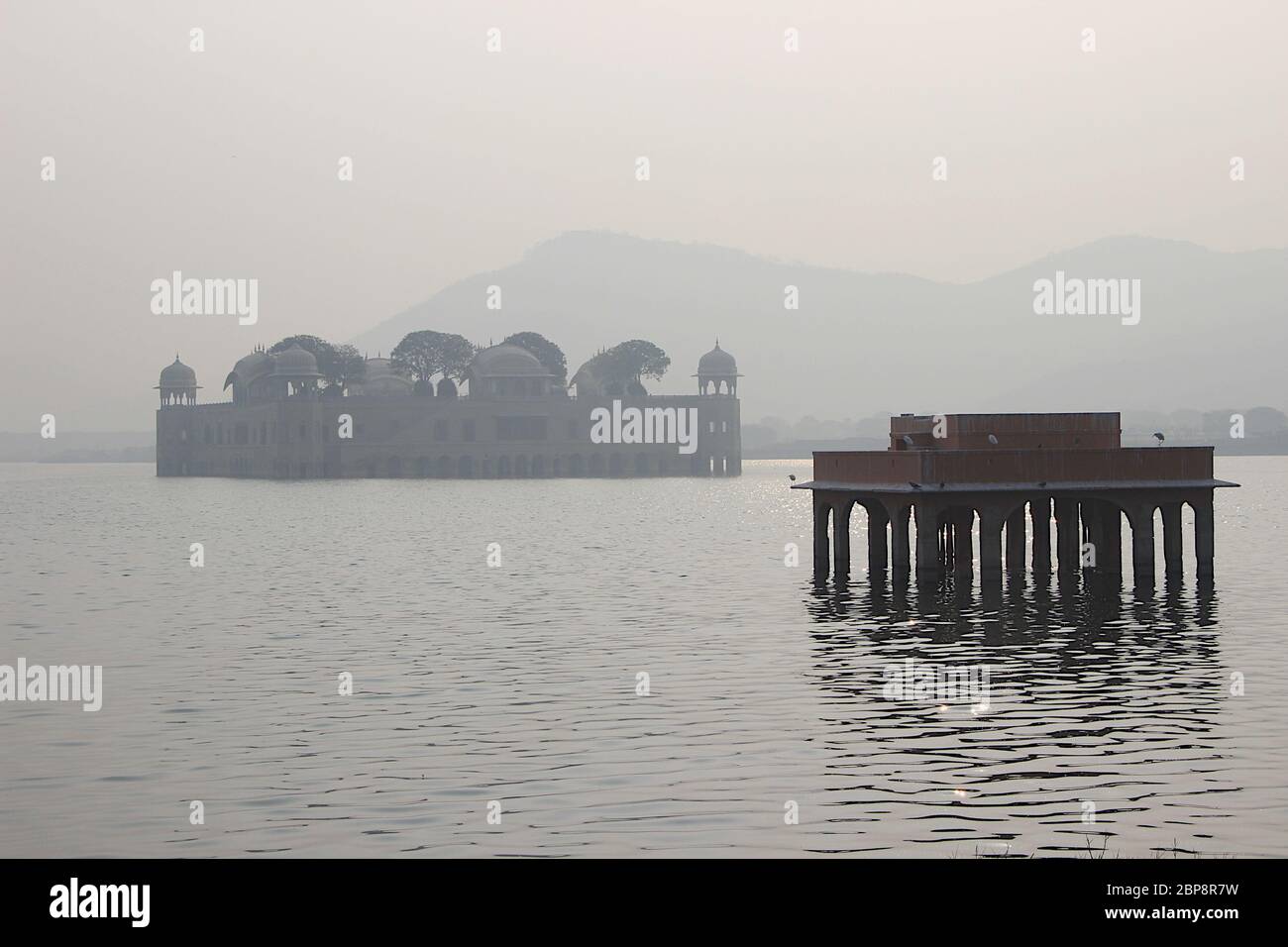 View of Jalmahal Summer Palace at Jaipur on a misty morning with silhouetted stone structure in the foreground, Rajasthan, India, Asia Stock Photo