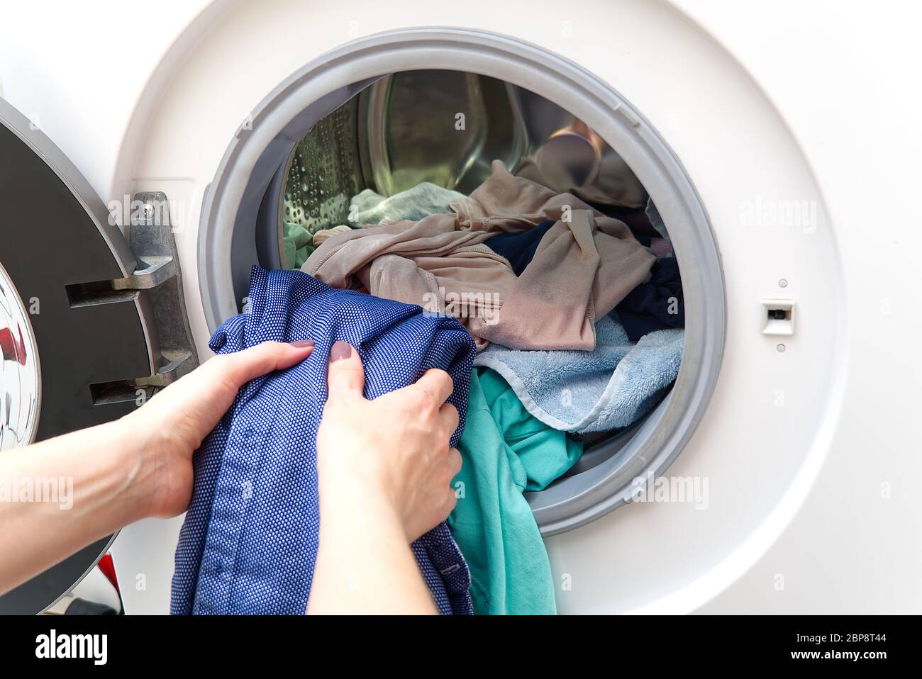girl takes out the laundry from the washing machine. woman puts clothes