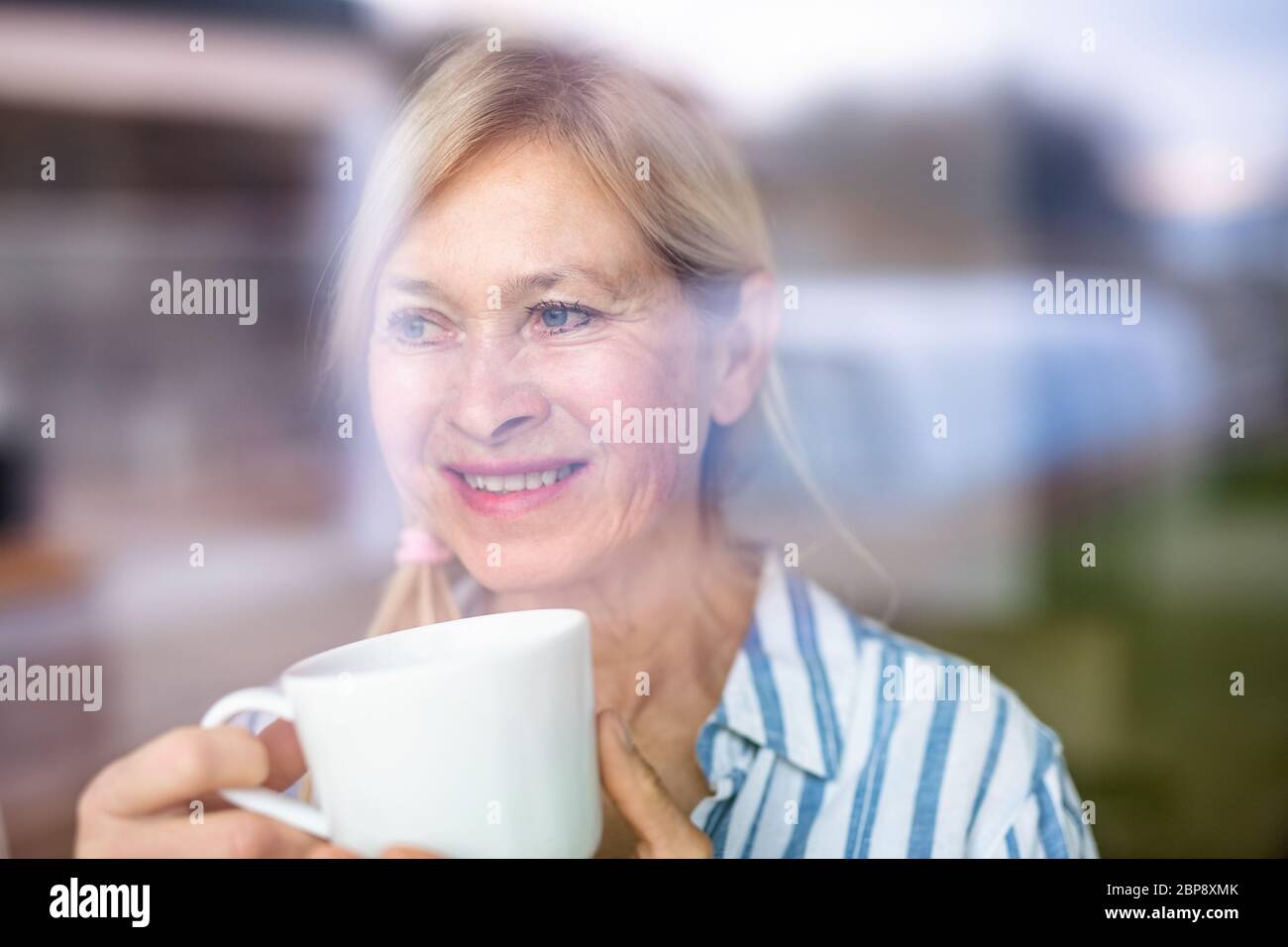 Portrait of senior woman with cup of coffee indoors at home. Stock Photo