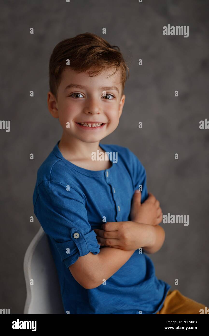 5 year old boy blue shirt and yellow pants studio portrait on gray
