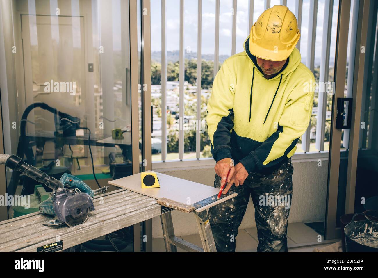 Man marking marks with pencil on a tile to be cut. Laying ceramic floor