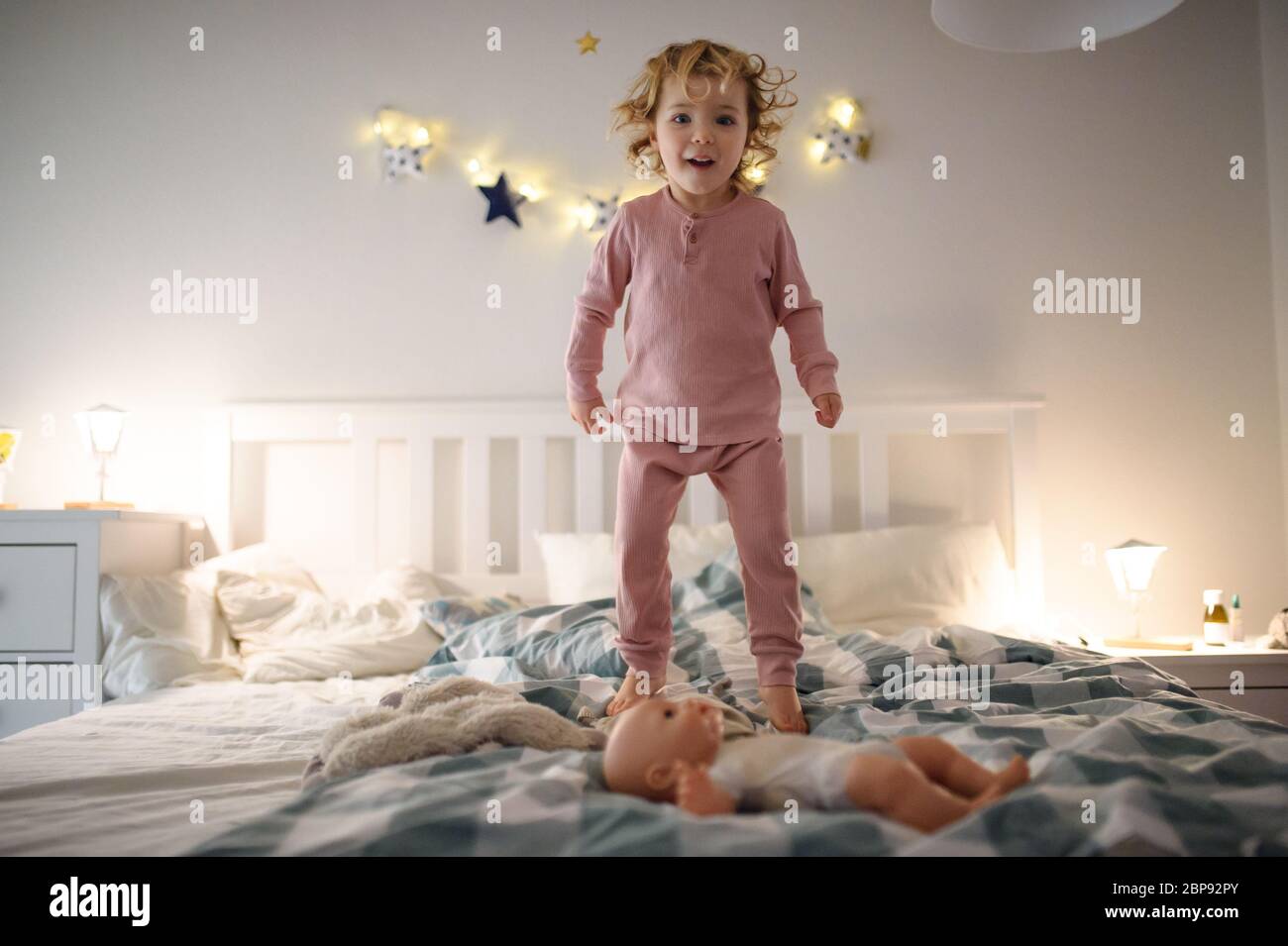 Small toddler girl jumping on bed indoors at home, having fun Stock