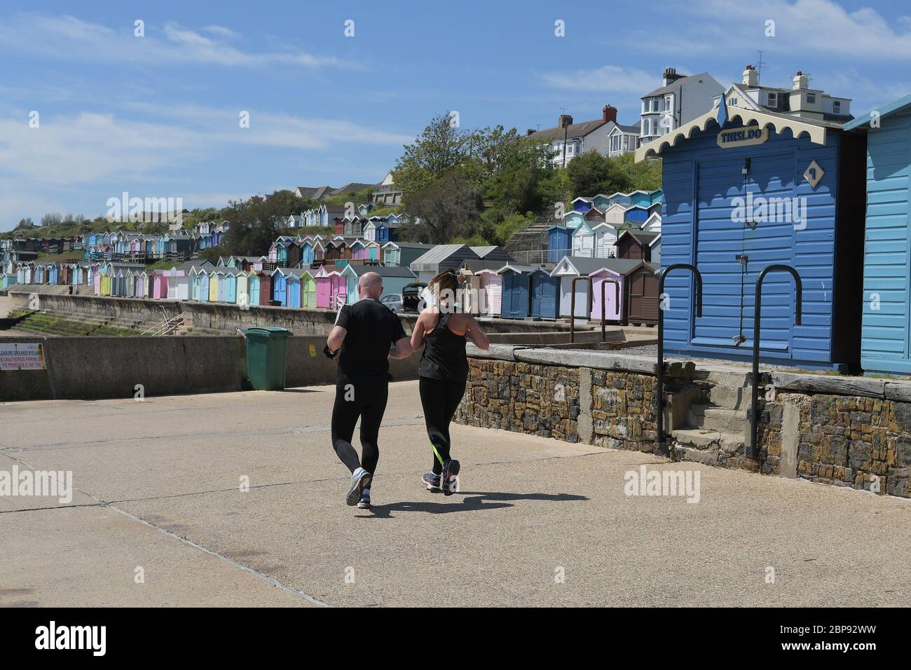 Joggers Run past the seaside towns multi coloured beach huts Stock