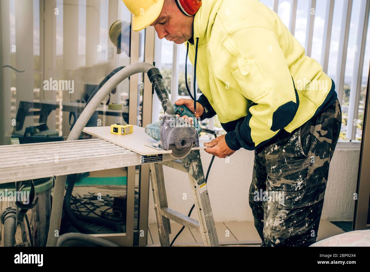 Master cuts the tile using an angle grinder with special diamond disc. Stock Photo
