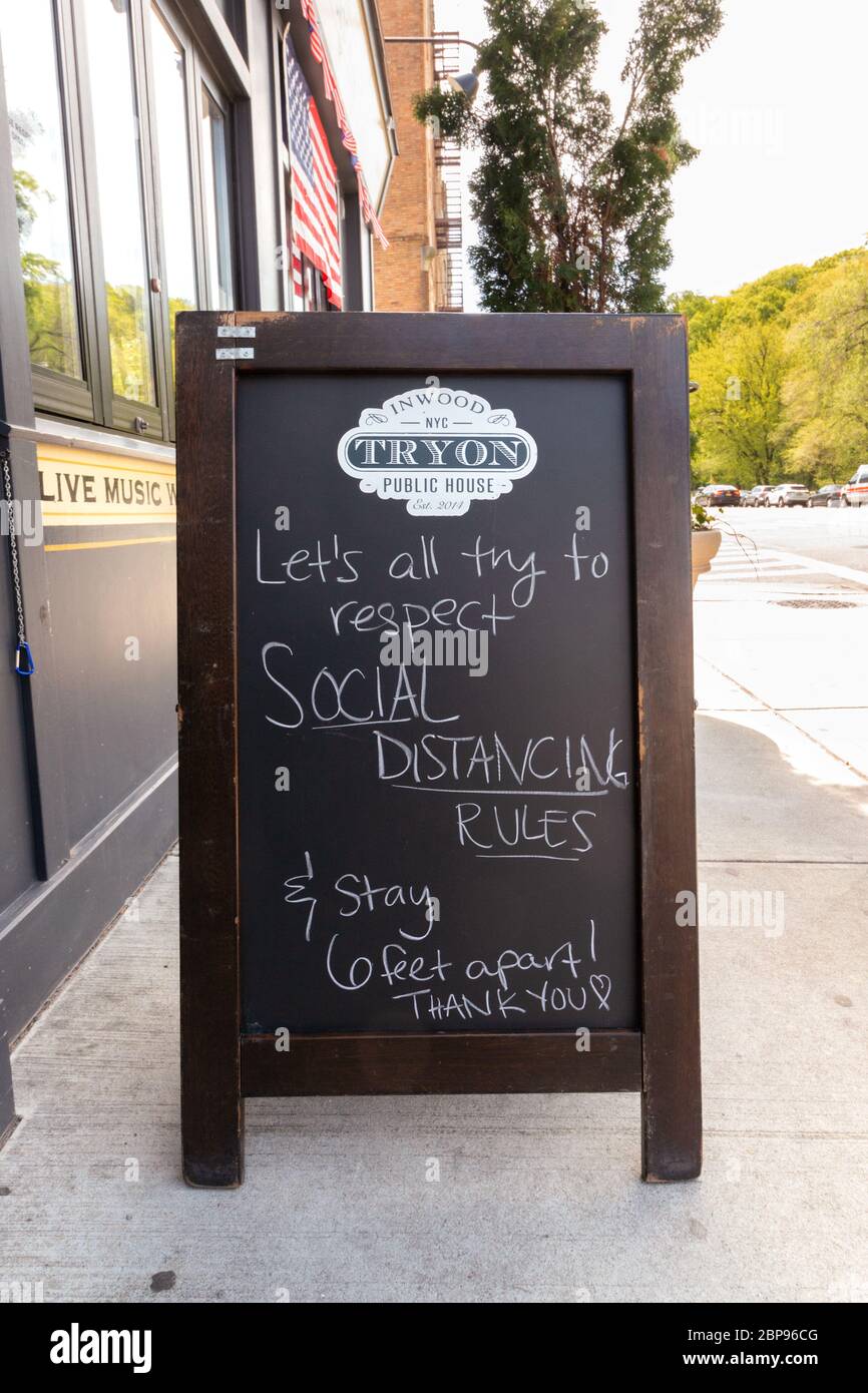 sidewalk chalkboard or blackboard sign in front of a pub reminding people to social distance and stay six feet apart due to coronavirus or covid-19 Stock Photo