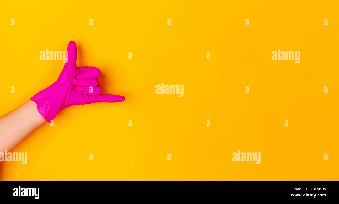 Hand in pink protective rubber glove isolated on yellow studio ...